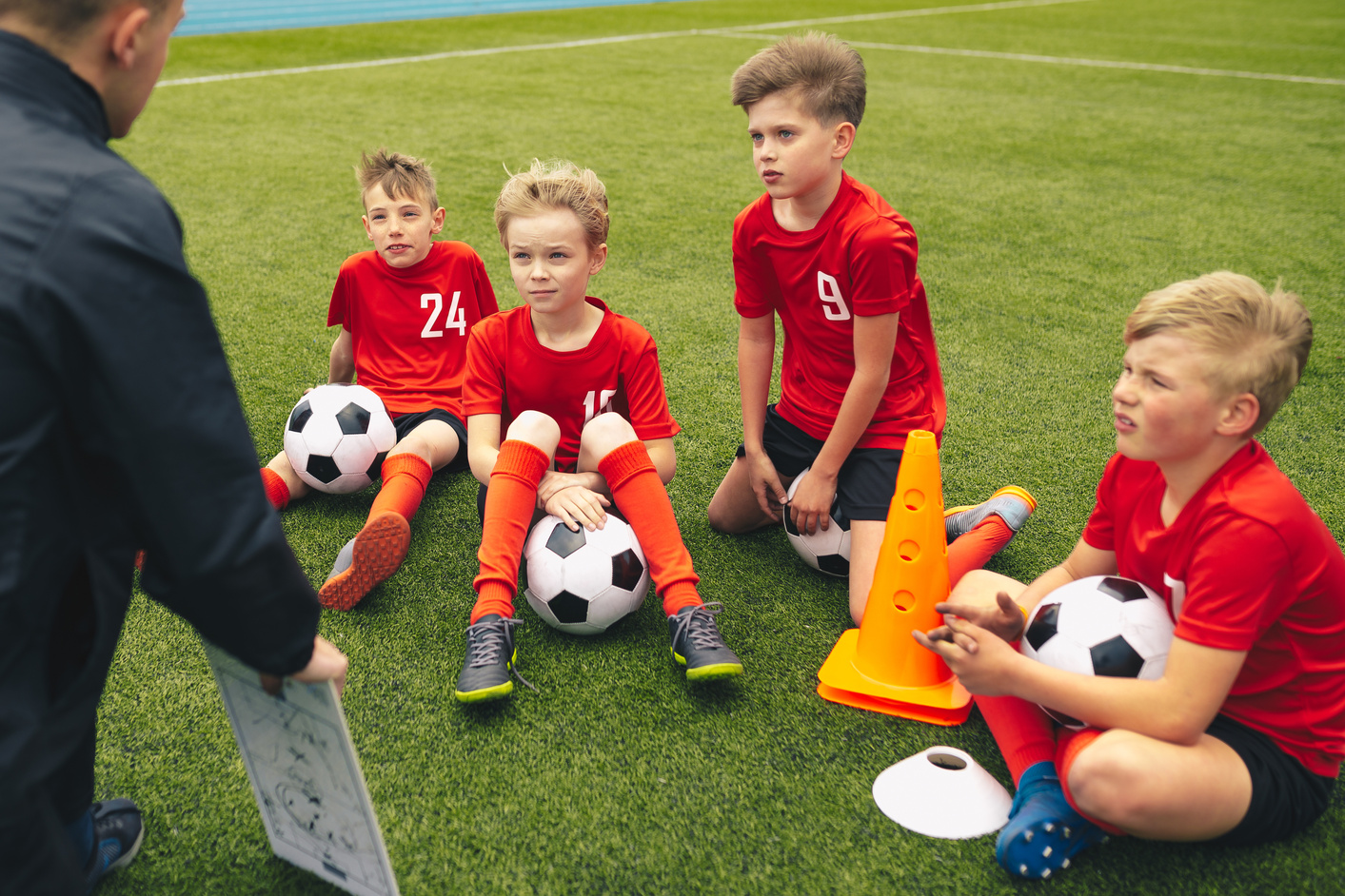 Football coach coaching children. Soccer football training session for children. Young coach teaching kids on football field. Football tactic education. Coach explains the strategy of the game